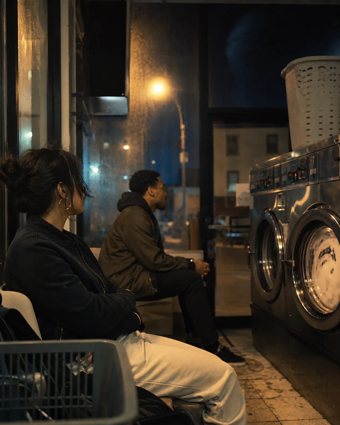 Two people share a quiet late-night moment in a laundromat