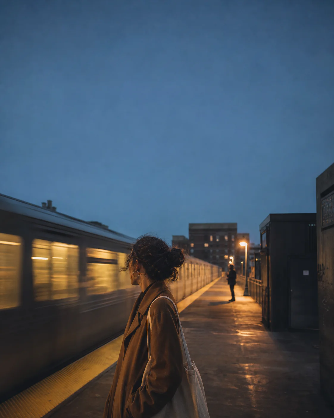 A woman pauses on a city train platform at night